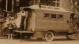 Sepia tone photo of women with a GFS branded caravan in 1920q
